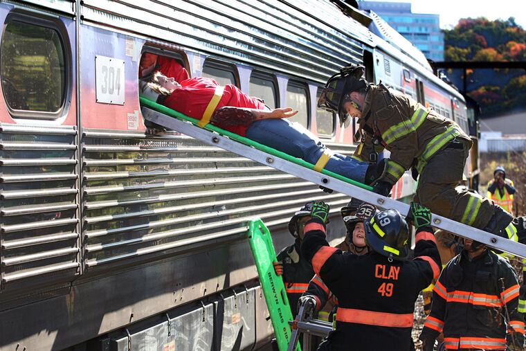 Tami Tray acts as an injured passenger removed from a train by Whitemarsh Fire Company responders during a drill Sunday along SEPTA's Manayunk/Norristown line that involved a collision and terror threat.