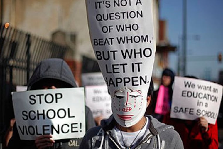Asian students with their faces covered by signs march to a school board meeting Wednesday to express concerns about 30 assaults at South Philadelphia High School last week. They say the attacks were racially motivated. (AP Photo / Matt Rourke)