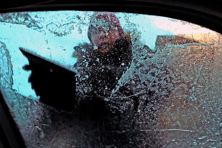 Marianna Cymbala fights to scrape the ice off her windows as sleet and freezing rain fall in St. Louis on Monday, Dec. 1, 2014.