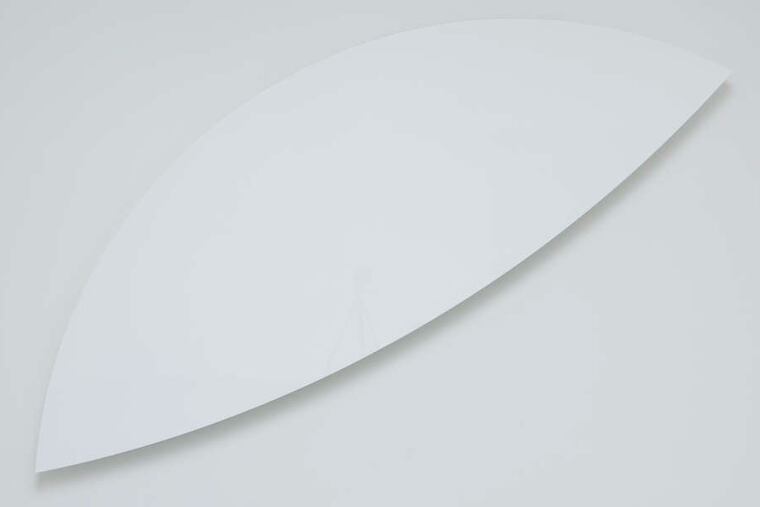 Kelly's "Two Curves" (2012) is elegantly minimal. The top edge nearly dissolves against the pale wall, while the bottom curve, accented by deep shadow, stands out in bold relief.