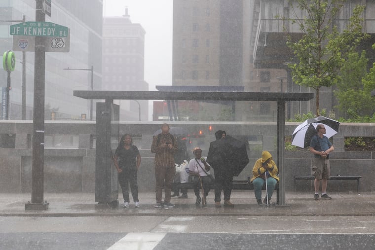 People waiting at a SEPTA bus stop as rain poured down in Center City along John F. Kennedy Boulevard earlier this month.