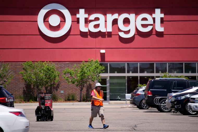A worker collects shopping carts in the parking lot of a Target store in 2021 in Highlands Ranch, Colo.