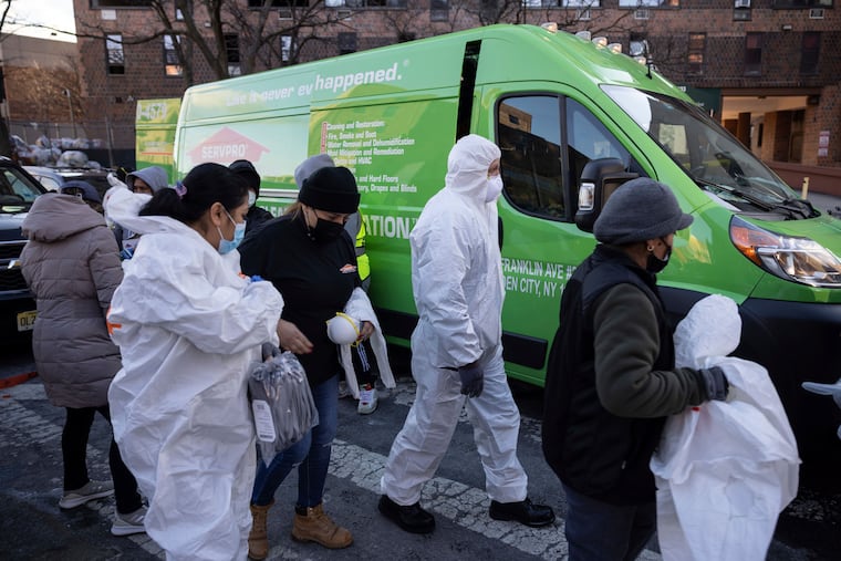 Cleaning and recovery crews work outside the apartment building in the Bronx on Monday.