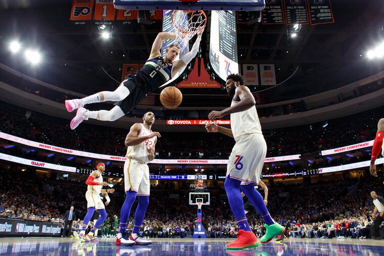 Milwaukee Bucks' Donte DiVincenzo, left, dunking on the 76ers on Christmas Day.