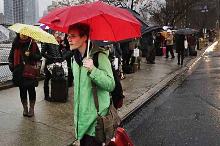 Passengers wait for a BoltBus to arrive during a light rain, Wednesday, Nov. 27, 2013 in New York. Some unusually warm December temperatures are on tap for Philadelphia over the next few days. (AP Photo/Mark Lennihan/File)