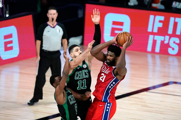 Joel Embiid (21) looks to pass the ball as Kemba Walker (8) and Enes Kanter (11) double-team him. Sixers coach Brett Brown believes spacing four players on the perimeter will increase Embiid's double-teams.