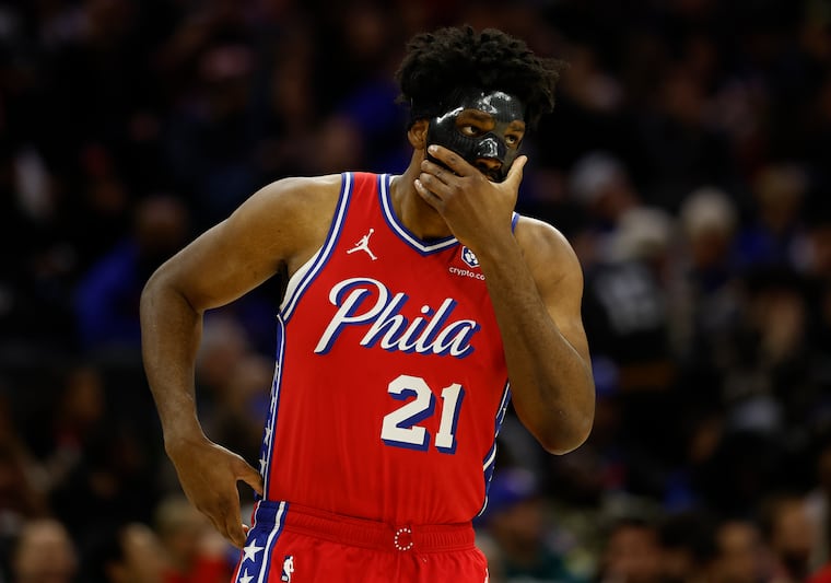Sixers center Joel Embiid adjusts his mask during a game against the Charlotte Hornets in 2024.