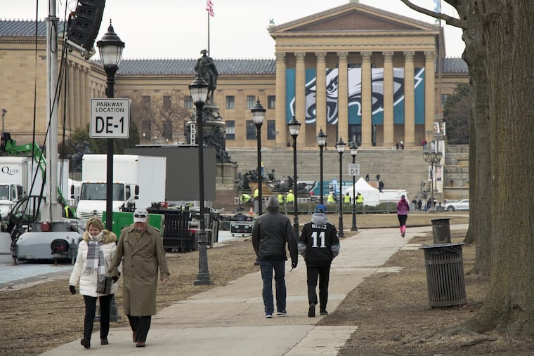 Fans walk down Benjamin Franklin Parkway as the city continues to get ready for the Super Bowl parade. The Philadelphia Museum of Art is among the institutions closing for the celebration.