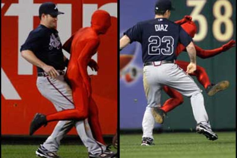 Braves left fielder Matt Diaz helps out the security by tripping an intruder in the seventh inning. (Ron Cortes / Yong Kim / Staff Photographers)