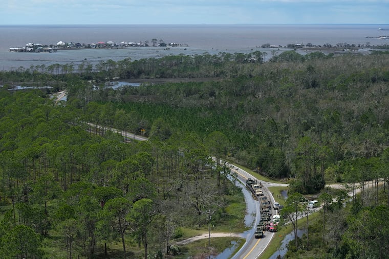 In this photo made in a flight provided by mediccorps.org, National Guardsmen and other first responders gather on a road leading to Keaton Beach and Dark Island, back left, near Fish Creek, Fla., following the passage of Hurricane Idalia on Wednesday, Aug. 30, 2023.