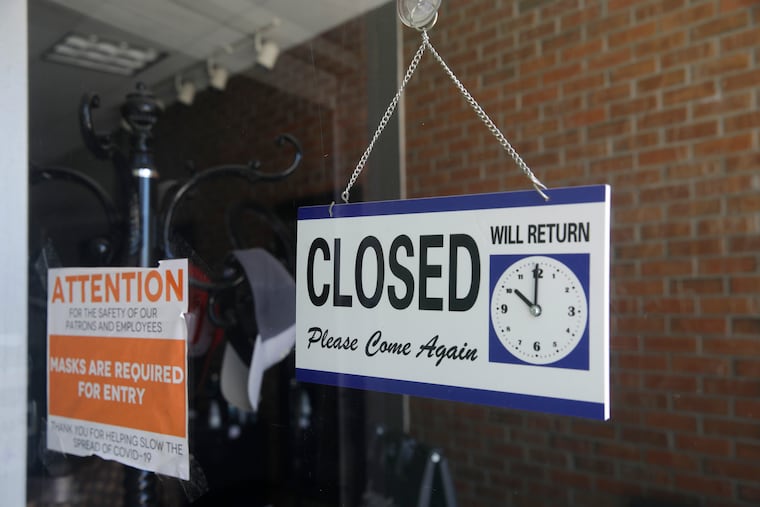 In this July 18, 2020 photo, a closed sign hangs in the window of a barber shop in Burbank, Calif.