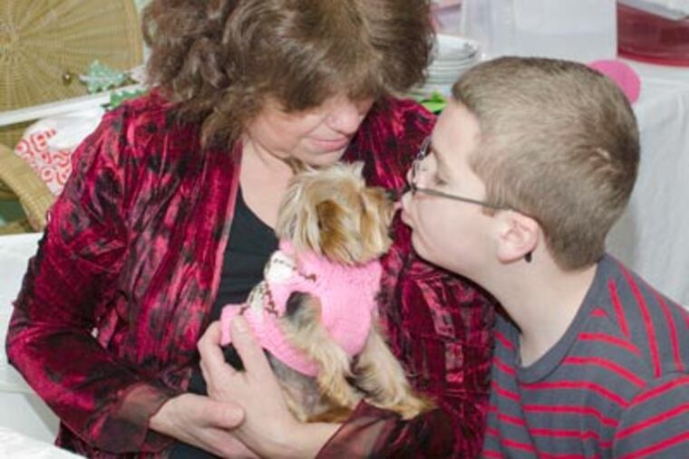 Lucy, a micro Yorky, with owner Sally Leone Montufar, gets a kiss from Sean Hebron, 11, of Jackson, N.J. Lucy, a therapy dog, is "the world's smallest working dog," Guinness says. (Howie Williams / Associated Press)