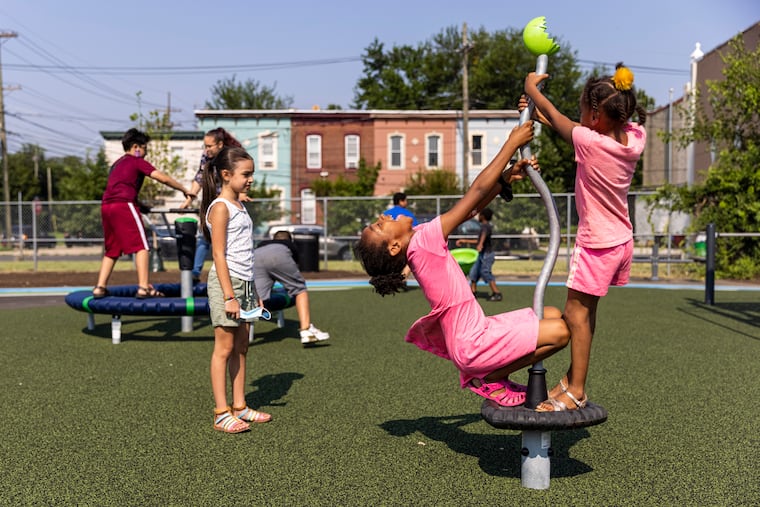 Alani Falcon, 2nd grader at Coopers Poynte Family School, (left), watches fellow students Envy Custis, 2nd grader, (center), and Aniya Custis, 1st grader, (right), play in the park at Dominick Andujar Park in Camden on Tuesday.