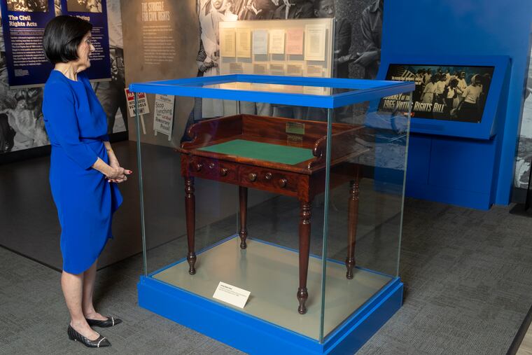 Luci Baines Johnson looks at the desk that President Lyndon B. Johnson sat at in the President's Room at the U.S. Capitol to sign the Voting Rights Act of 1965, on display at the LBJ Presidential Library on May 16, 2023.