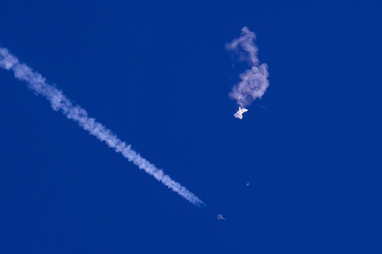 The remnants of a large balloon drift above the Atlantic Ocean, just off the coast of South Carolina, with a fighter jet and its contrail seen below it on Saturday.