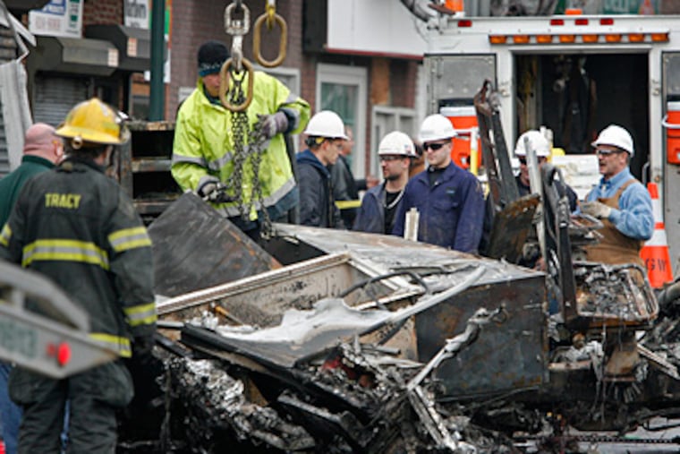 Workers and firefighters watch as the remains of a PGW truck are removed from the site of the Jan. 18, 2011, gas-main explosion in the Tacony section. (Alejandro A. Alvarez / Staff Photographer)