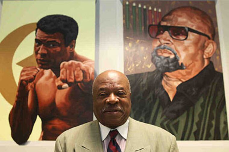 Founder Walter D. Palmer, at Palmer Leadership Learning Charter in North Phila., is flanked by portraits of social activists Muhammed Ali (left) and Kwanzaa pioneer Maulana Karenga. (Juliette Lynch / Staff Photographer)