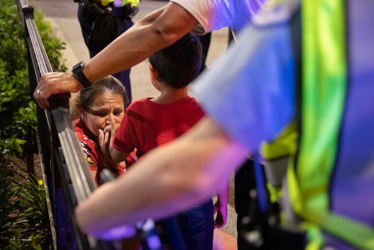 In this Thursday, July 4, 2019, photo, Chicago Police Department officers stand guard while a woman comforts her son, who had panicked after reports of stabbings and threatening injuries after the Fourth of July celebrations at Chicago's Navy Pier.