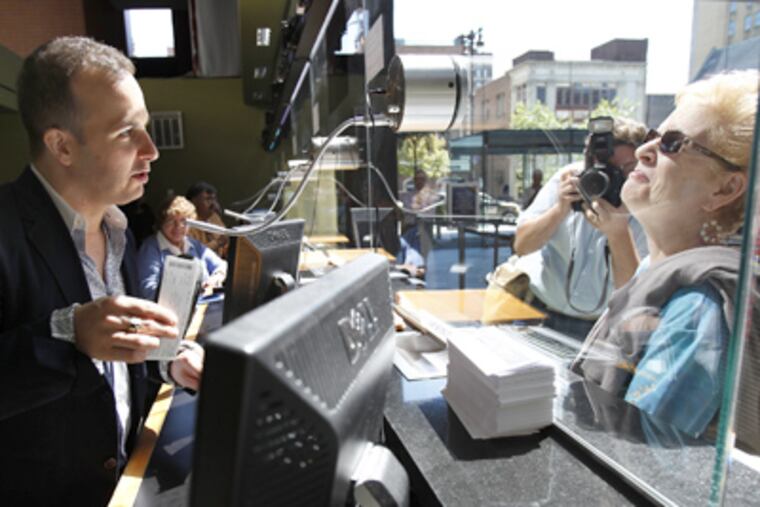 Philadelphia Orchestra music director Yannick Nézet-Séguin prepares to sell two concert tickets to Carolyn Platt of Abington. (David Maialetti / Staff Photographer)