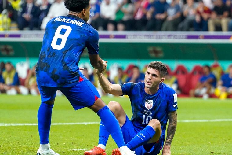 U.S. midfielder Weston McKennie lends a hand to Christian Pulisic during the match against England at Al Bayt Stadium on Nov. 25.
