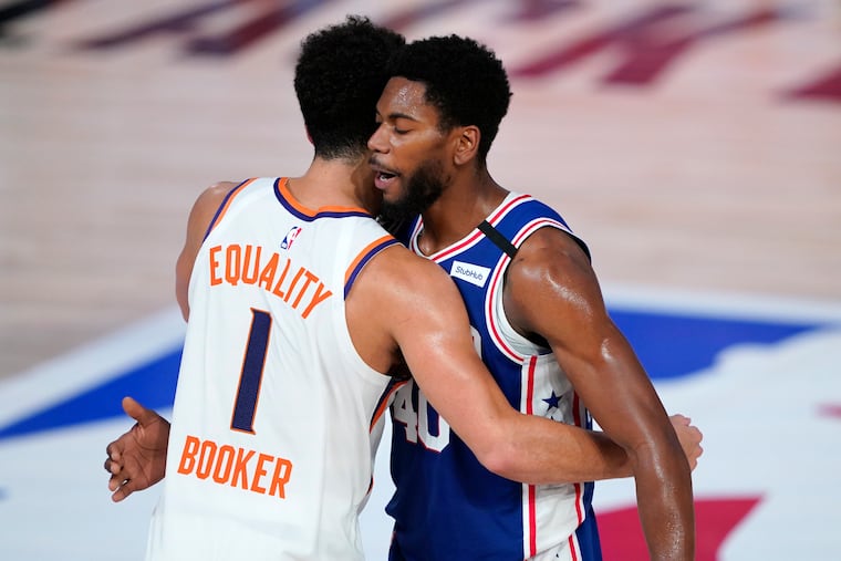 Phoenix Suns guard Devin Booker, left, greets Philadelphia 76ers forward Glenn Robinson III, right, after Tuesday's game. It was the second and last seeding game he's played in at the NBA bubble.