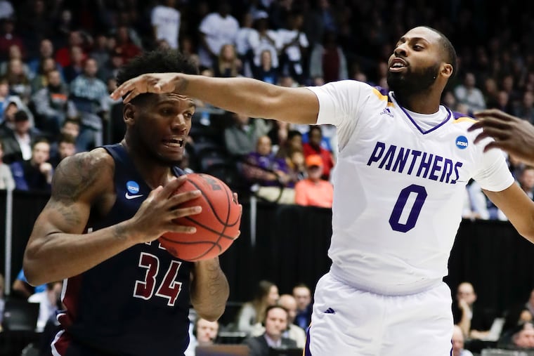 Fairleigh Dickinson forward Mike Holloway Jr. holds the basketball while defended by Prairie View A&M guard Chancellor Ellis.
