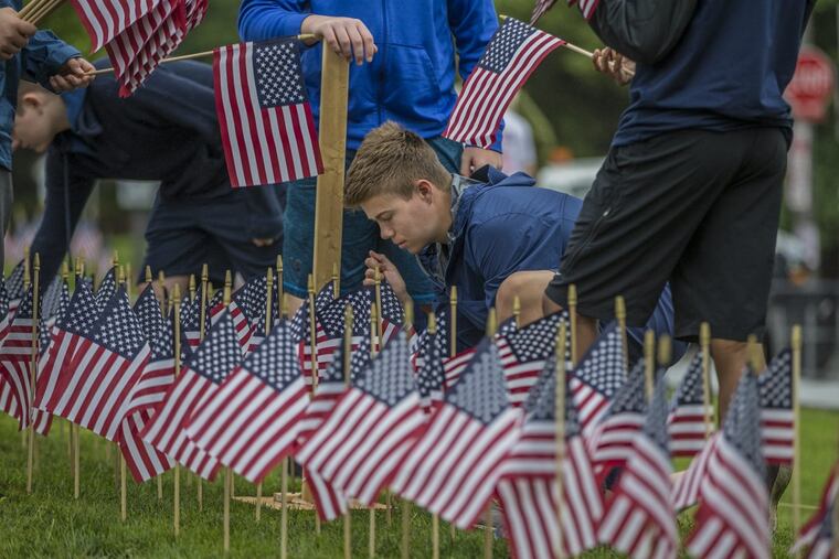 Dan Timoney, 16, of La Salle College High School, places an American flag at a precise point at the Vietnam Veterans Memorial.