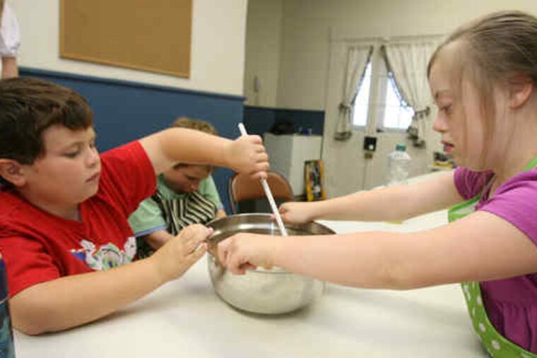 Kevin Flocco (left) and Annie Boyle work together as they stir their brownie mix. They are partof a cooking class run by KidsAhead, a program that helps autistic children build life skills.