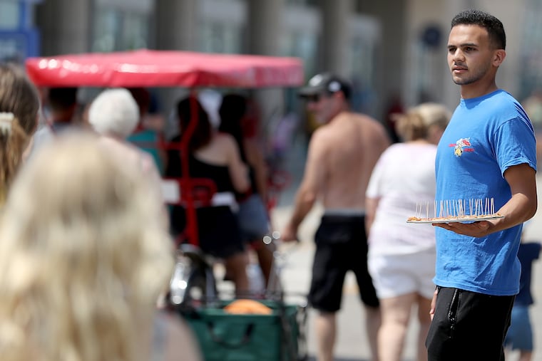 Abdul Abham holds a tray of free samples of pizza outside of Crazy Junky Pizza on the boardwalk in Wildwood, N.J. on Sunday, July 17.