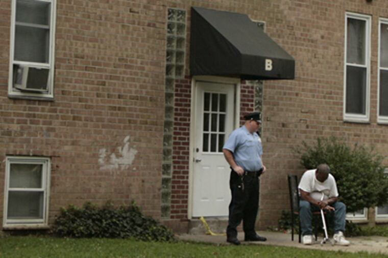 As a police officer keeps the entrance secure, William Outlaw sits outside the Fairmount Manor apartment building where his niece was found dead this morning. (Elizabeth Robertson / Staff Photographer)