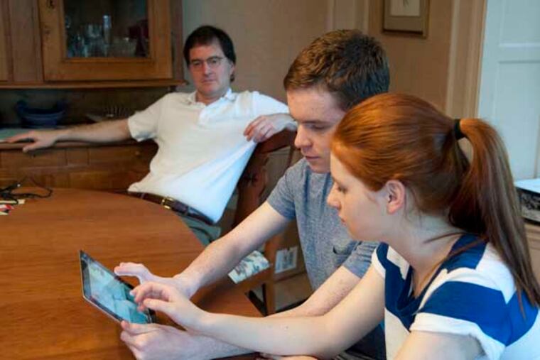 Anna and Karl Meyer, brother and sister beta testers for "ChemCrafter," a virtual chemistry set for the iPad, play the game in their home in Wynnewood as their father Craig watches in the background. ( RON TARVER / Staff Photographer ) April 11 2014