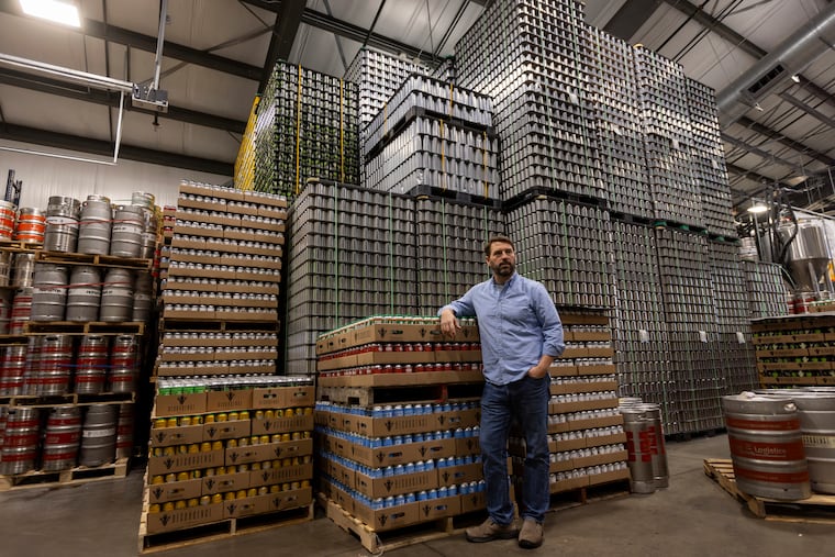 Jeff Ware, president of Resurgence Brewing Co., poses for a portrait near a stockpile of aluminum cans, which are sourced from Canada, Thursday, Feb. 27, 2025, in Buffalo, N.Y.