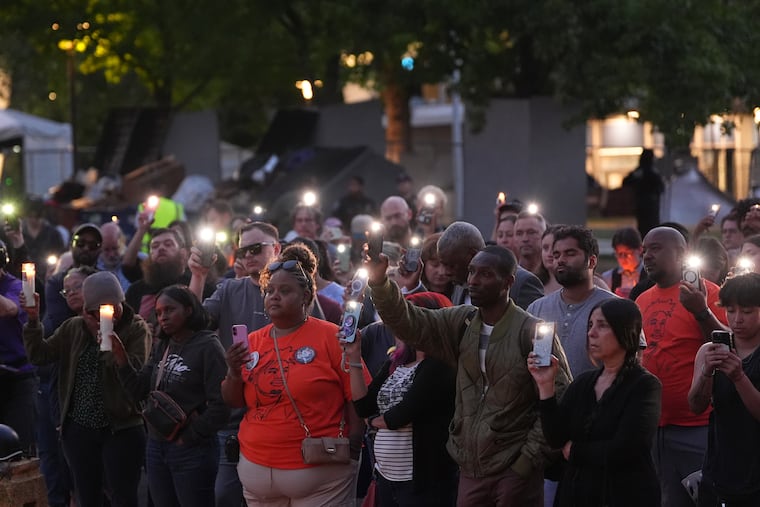 People hold smartphones with flashlights during the vigil for victims the day after a shooting at Seattle Center during the Bite of Seattle food festival, Monday, July 27, 2026, in Seattle.