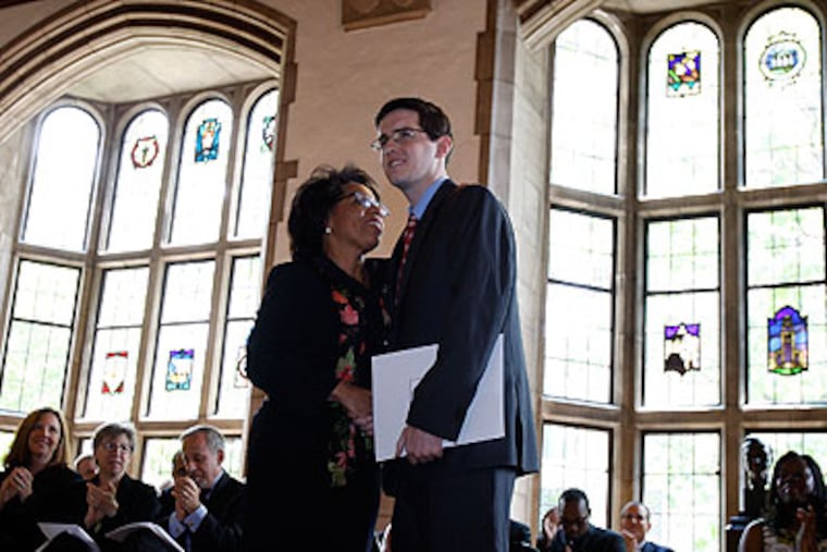 Temple Law School Dean JoAnne Epps, left, hugs Anthony Foltz, a Temple University Law student, after he received the Crossen Award Thursday. The award is given to a graduate who overcame adversity and demonstrated perseverance. Foltz was struck by a car while crossing the Ben Franklin Parkway last year. (David Maialetti / Staff Photographer)