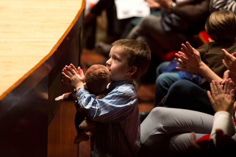 A young member of the audience claps for the Philadelphia Orchestra at its family concert. Budget cuts curtailed the production, but not the enjoyment.