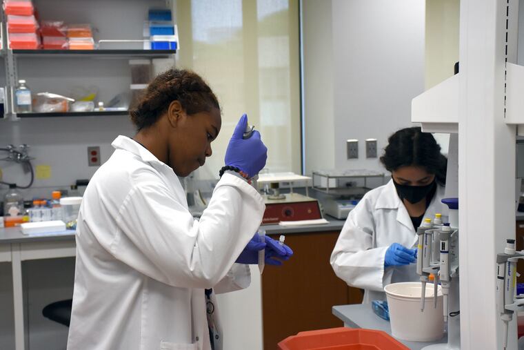 Philadelphia high schoolers Tiffani Billups (left) and Amal Oubarri use pipettes at the Wistar Institute, where they contributed to a new study of a possible treatment for HIV.