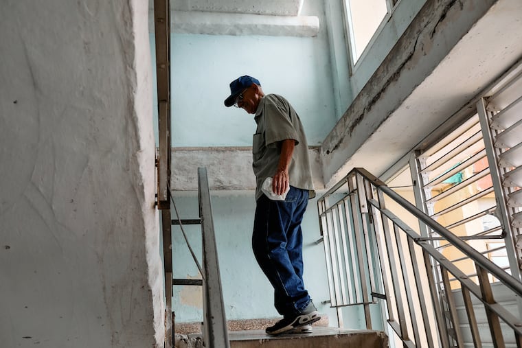 Santiago Batista Virgilio, 84, climbs the stairs to his apartment in a residential complex of five 18-story buildings in Santiago de Cuba on May 13. The elevator no longer functions most of the time.