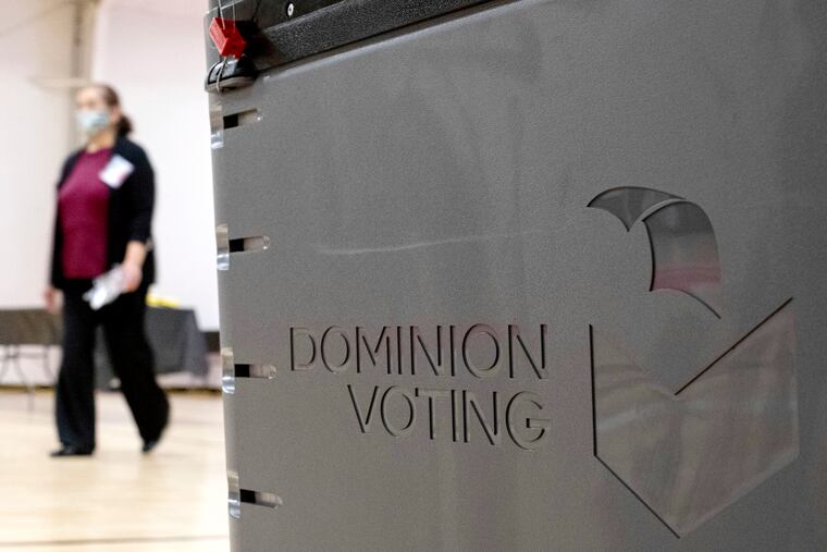 A worker passes a Dominion Voting ballot scanner at a Georgia polling place in 2021.