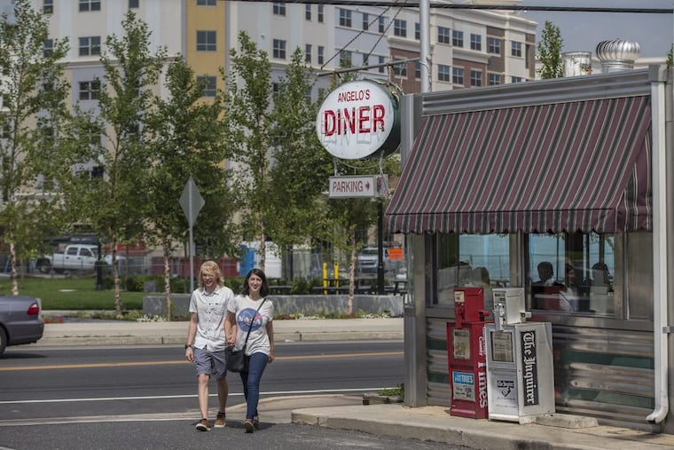 A couple walks out of Angelo’s, a downtown Glassboro institution with a view of the new buildings of the Rowan Boulevard project.