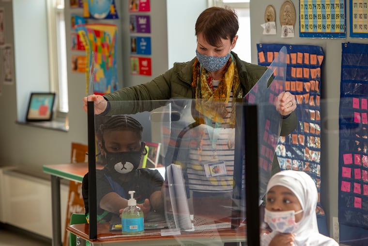 More Philadelphia students will be eligible to return to in-person learning on April 26. Students in grades 3-5 and complex needs students in grades 6-8 can opt in to hybrid learning, the Philadelphia School District announced Thursday. In this file photo, a teacher adjusts a student's desk shield at Overbrook Educational Center in West Philadelphia.