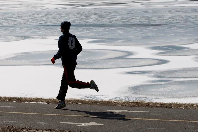 A jogger runs by a frozen section of the Schuylkill River near the Girard Ave. Bridge in 2015.