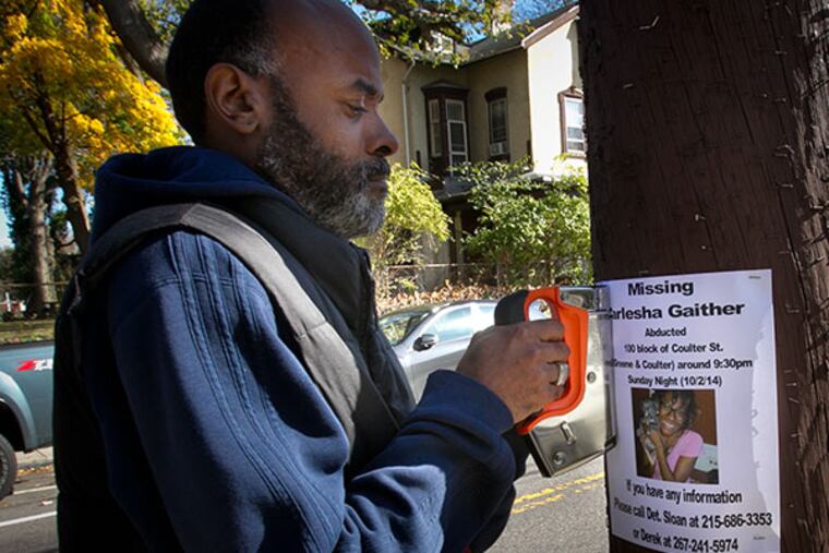 Carl Freeland, father of Carlesha Gaither of Germantown staples a flyer with information on his missing daughter allegedly abducted from W. Coulter St at Greene St. on Sunday, November 2, 2014. ( ALEJANDRO A. ALVAREZ / STAFF PHOTOGRAPHER )
