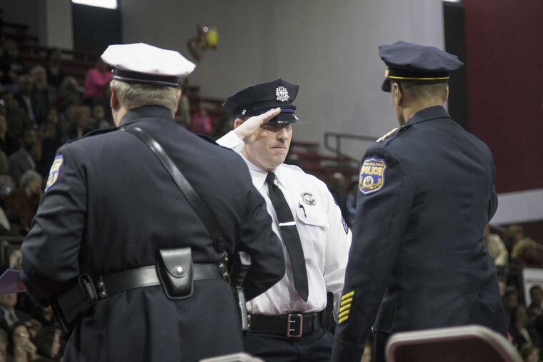 Police Commissioner Richard J. Ross Jr. (right) salutes newly promoted sergeant Eric Brooks (white shirt).