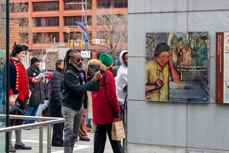Michael Coard of the Avenging the Ancestors Coalition records video of speakers at the 15th anniversary celebration of the President's House Site exhibit in Independence National Historical Park on Sunday, Dec. 21, 2025.
