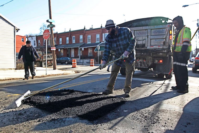 On 42d Street in Mantua, city worker Ohrante Carter spreads asphalt in a pothole, one of at least 12 the crew repaired Thursday.
