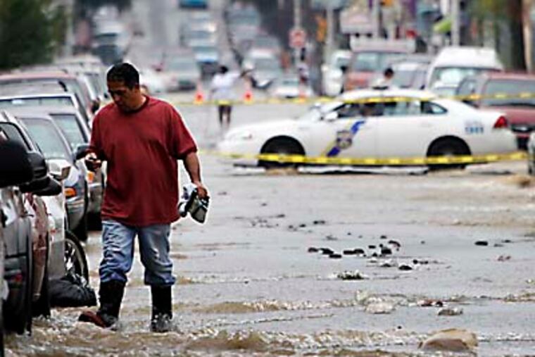 Residents near North Front and Tioga streets watch water flow down Front Street after a water main broke early Wednesday, Aug. 1, 2012. (Alejandro A. Alvarez / Staff Photographer)