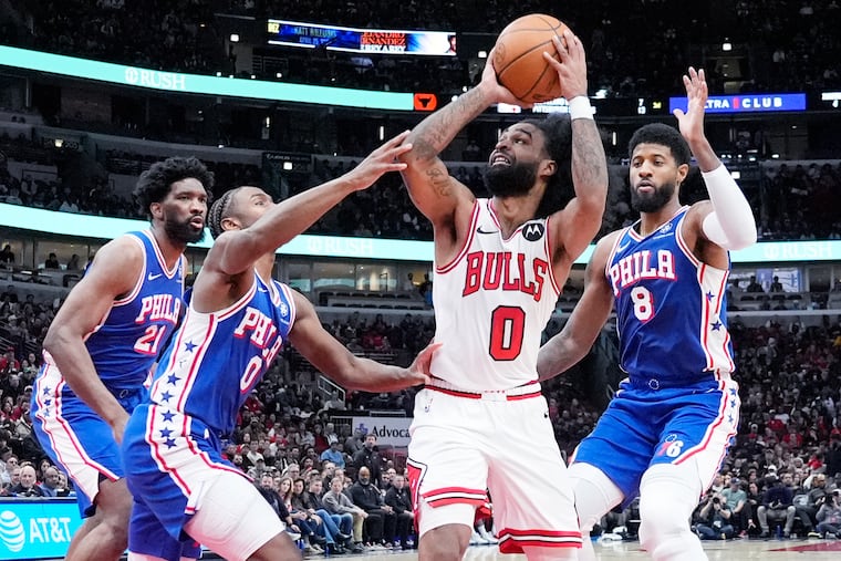 Chicago Bulls guard Coby White looks to get off a shot against Sixers defenders (from left) Joel Embiid, Tyrese Maxey, and Paul George.