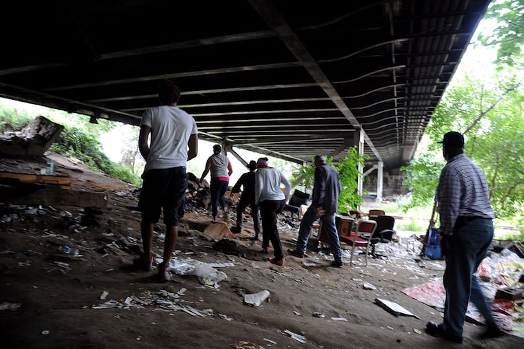 Charito Morales, a registered nurse and advocate, leads a group through “El Campamento,” a camp of homeless drug users under a railroad bridge in Fairhill. (TOM GRALISH / Staff Photographer)