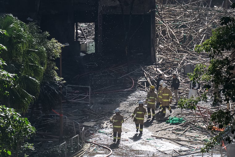 Firefighters walk through the burned buildings after the deadly fire at Wang Fuk Court, a residential estate in Hong Kong.