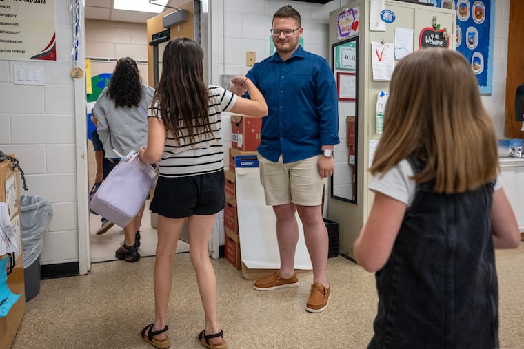 Teacher Jeffrey Martine greets students at Rossi Elementary in Vineland last week. The school district eased the dress code for teachers this spring by allowing them to wear jeans - a move to boost morale as the school year concludes.